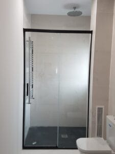 Mampara de dutxa de vidre amb porta corredissa.